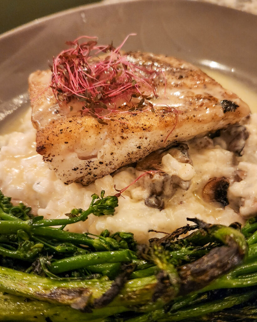 WOOD GRILLED HALIBUT over wild mushroom Risotto, in a lemon butter sauce with charred broccolini